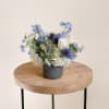 Blue and white floral arrangement in a dark vase on a wooden table