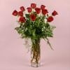 Red roses arranged in a tall clear glass vase