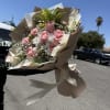 Handheld bouquet of pink roses and white flowers wrapped in beige paper