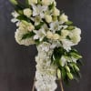 White floral cross arrangement on an easel with lilies and roses