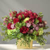 Red roses and pink flowers arranged in a gold box vase