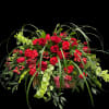Casket spray of vivid red roses and carnations with trailing greenery 