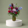 Mixed bouquet of red, purple, and blue flowers in a glass vase