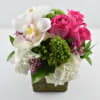 Compact arrangement of white hydrangeas, pink roses, and a white orchid in a green cube vase