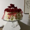Red and white floral arrangement in a glass pedestal bowl with ribbon