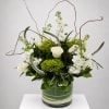 White roses and green blooms in a glass vase with curly branches