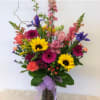 Colorful mixed bouquet in a glass vase with a purple ribbon