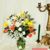 Mixed bouquet of white, yellow, orange, and purple flowers in a glass vase