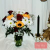 Bouquet of red roses, white daisies, and yellow sunflowers in a glass vase