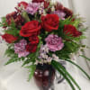 Bouquet of red roses and purple carnations in a burgundy vase