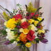 Mixed bouquet of roses, white blooms, and purple accents in a glass vase