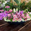 Pink roses and lilies arranged in a low black container