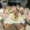 Pink and white roses arranged in a low white container