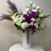 White roses and purple orchids in a tall white vase