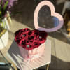 Heart-shaped box of red roses with a pink heart topper