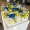 Box arrangement of blue and lime roses with white hydrangeas