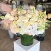 Cream and blush bouquet of roses, orchids, and snapdragons in a glass vase