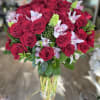 Bouquet of red roses with pale pink orchids in a clear glass vase