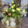 Green and lime floral arrangement in a white pedestal vase