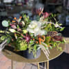Mixed floral arrangement with white blooms and orange berries in a dark container