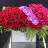 Red roses and pink hydrangeas with purple orchids in a white vase