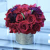 Red rose bouquet with purple flowers in a speckled vase