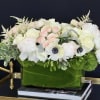 White and blush floral arrangement in a green glass vase