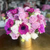 Pink and purple roses with white blooms in a gold vase