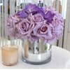 Lavender rose bouquet in a silver vase with a small candle beside it