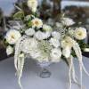 White floral arrangement in a clear glass vase with cascading blooms