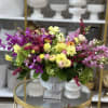 Colorful mixed flower arrangement in a white pedestal vase