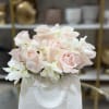 Blush pink roses and white orchids in a white gift bag