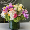 Colorful bouquet of orchids, roses, and hydrangeas in a glass vase