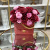 Red and pink roses arranged in a red handbag-shaped box