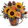 Sunflowers and peach roses arranged in a copper mug