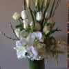 White calla lilies, roses, orchids, and lilies in a tall glass vase