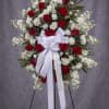 Standing red and white rose funeral spray with a white ribbon on an easel