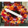 Large colorful funeral wreath with a white memorial ribbon