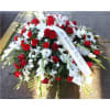 Red and white funeral spray with a memorial ribbon