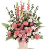 Pink and white floral arrangement in a square vase with a pink ribbon