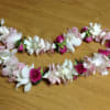 Two floral garlands of pink and white blossoms on a wooden surface