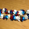 Two floral garlands with blue, white, and red flowers on a wooden surface