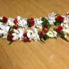 Red and white floral lei with ribbon on a wooden surface