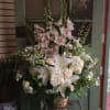 Tall white floral arrangement in a wicker basket with lilies and orchids
