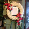 White floral wreath with pink roses and lilies on an easel