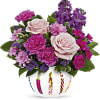 Pink and purple flower arrangement in a white vase with candle designs
