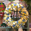 Large floral wreath with white lilies, blue hydrangeas, and yellow accents on an easel