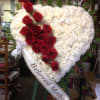 Heart-shaped white floral wreath with red roses and a ribbon