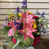 Mixed bouquet with pink lilies, roses, and purple flowers in a glass vase
