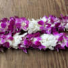 Two purple and white orchid leis on a wooden surface